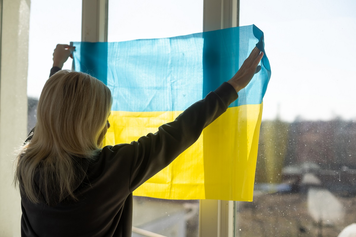 Ukrainka duvutsya u vikno z praporom