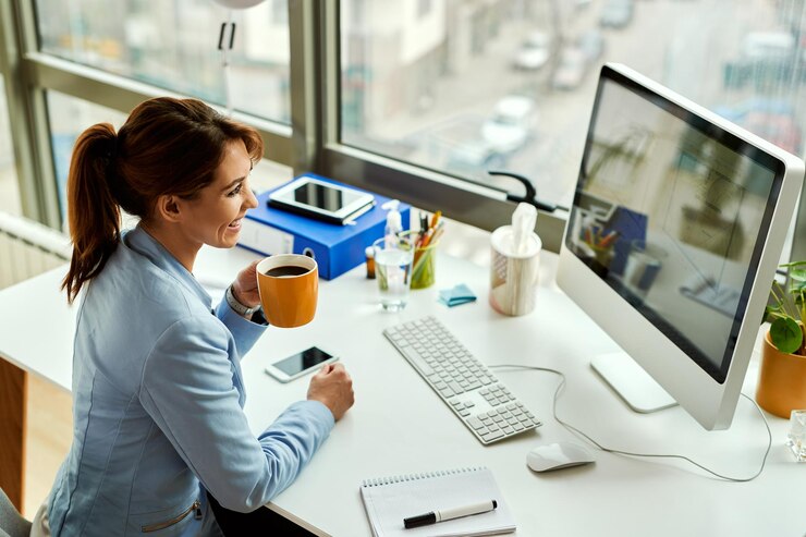 young happy businesswoman working on a computer and drinking coffee in the office 637285 5190